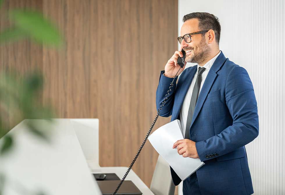 homme-veston-parle-telephone-faq-acarq-association-de-concessionnaires-automobiles-regionaux-quebec-saguenay-lac-saint-jean